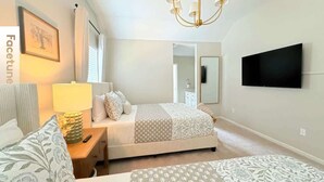 Un dormitorio con cama, mesitas de noche, lámpara, televisión y candelabro.