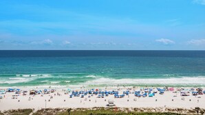 A beach with numerous umbrellas and people.