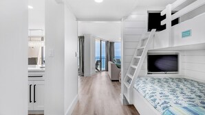 A modern, compact bedroom with a bunk bed, a television, and a balcony with a view.