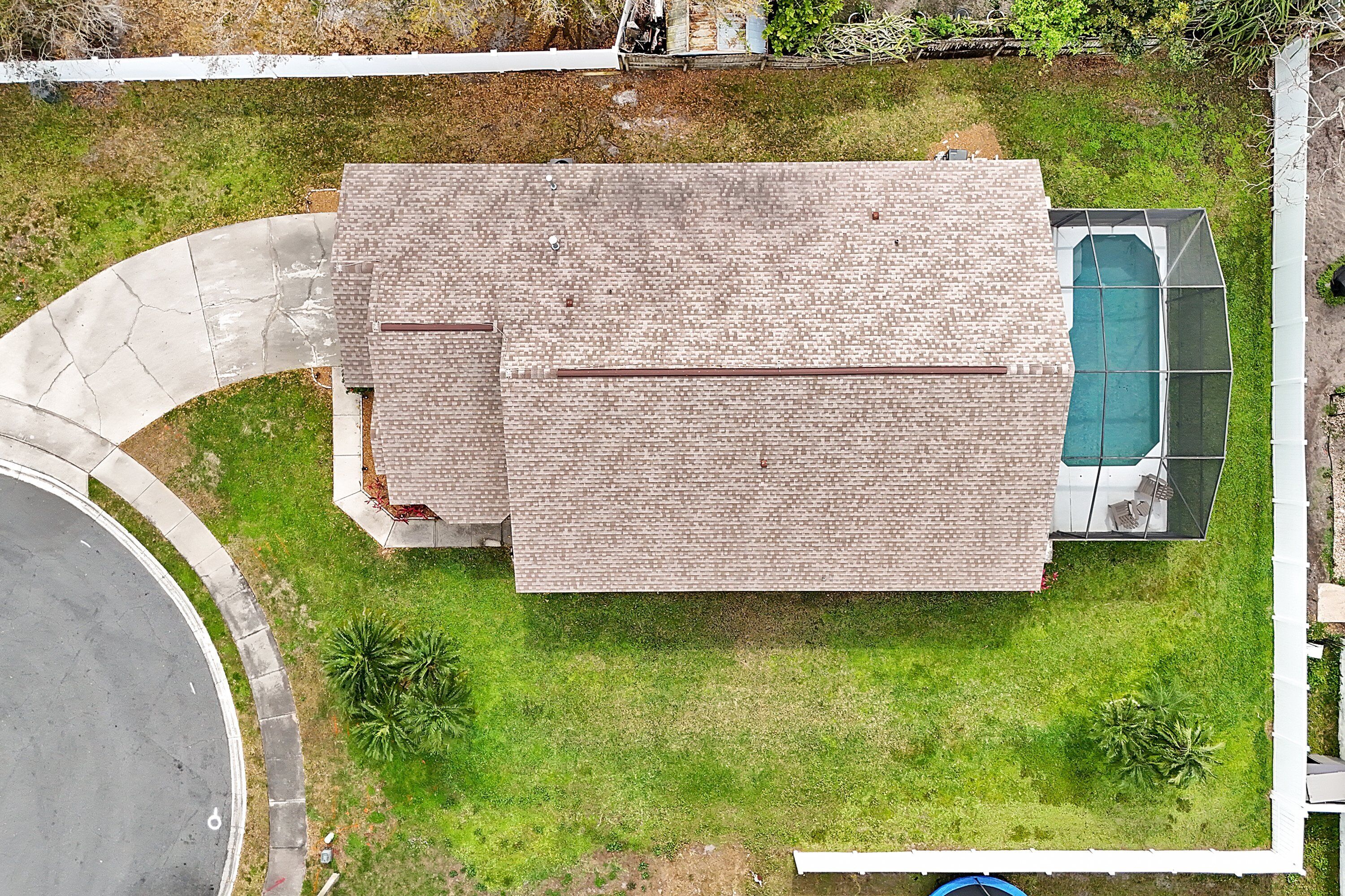 A two-story house with a large backyard, a swimming pool, and a driveway.