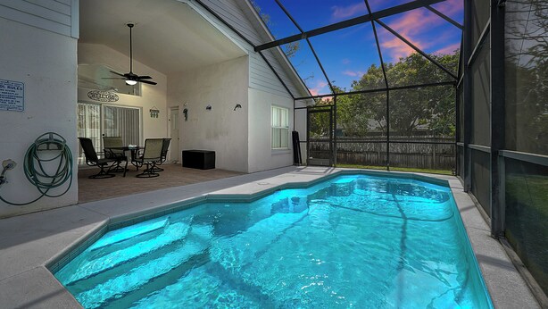 Ein Swimmingpool mit überdachter Terrasse, einem Deckenventilator und Blick auf den Himmel.