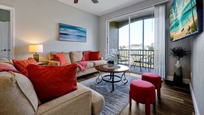 Ein Wohnzimmer mit einer Couch, roten Kissen, einem Couchtisch und einem Gemälde.