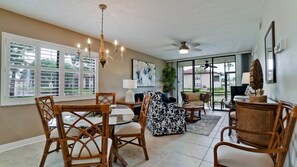 A spacious living area with a dining table, chairs, a sofa, and a ceiling fan.