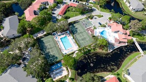 An aerial view of a residential area with a tennis court, swimming pool, and a dock. - WG-near Beaches and IMG, Pool, Tennis, Pickleball, Shorewalk condo 2 Bedroom/2 Bath lake view (Bradenton)