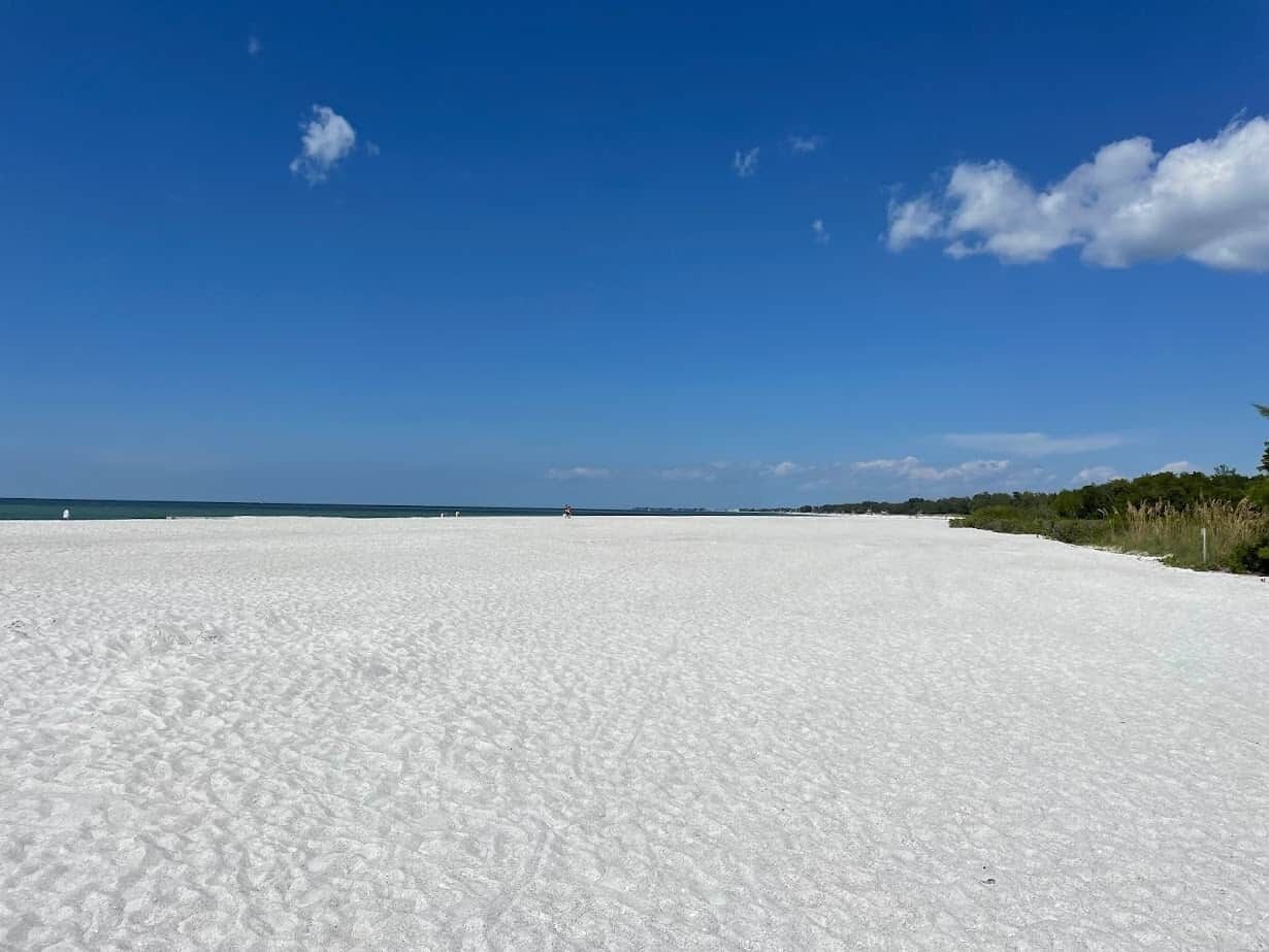 Une plage de sable blanc, sous un ciel bleu azur.