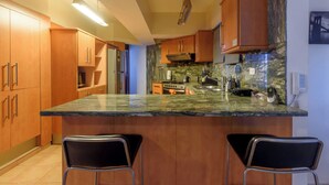 A kitchen with wooden cabinets, a granite countertop, and two bar stools.