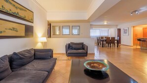 A modern living room with a sofa, a coffee table, and a dining area with chairs and a table.