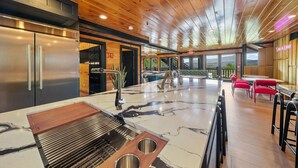 A modern kitchen with a marble island, stainless steel appliances, and a grill.