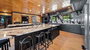 A modern kitchen with a marble countertop, black bar stools, and a large island.