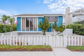 A two-story house with a blue exterior, white picket fence, and a small front yard with plants. - The Blue Pearl - 2 minute walk to the beach! (Del Mar)