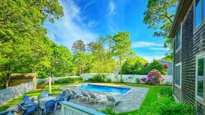 A backyard with a swimming pool, deck chairs, and a wooden deck. - Overlook Poolside Getaway Heated Pool (May - Oct 20th) (East Falmouth)