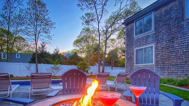 An outdoor patio with a fire pit, lounge chairs, and a pool. - Overlook Poolside Getaway Heated Pool (May - Oct 20th) (East Falmouth)