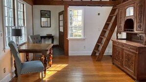 Une pièce avec un plancher en bois, une table à manger avec des chaises, un escalier et un meuble en bois.