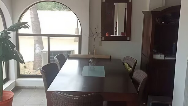 A dining area with a table, chairs, a ceiling fan, a large window, and a potted plant. - Hostal Hab 12, Campo de Golf, En Zona Hotelera, Barra, Playa (San José del Cabo)