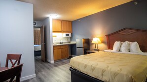 Une chambre d’hôtel de taille réduite, équipée d’un lit, d’un bureau, d’une chaise, d’un four à micro-ondes et d’un réfrigérateur.