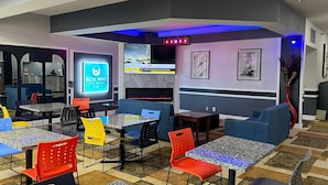 Un espace de détente moderne avec des tables et des chaises, un écran de télévision diffusant les actualités et une cheminée.