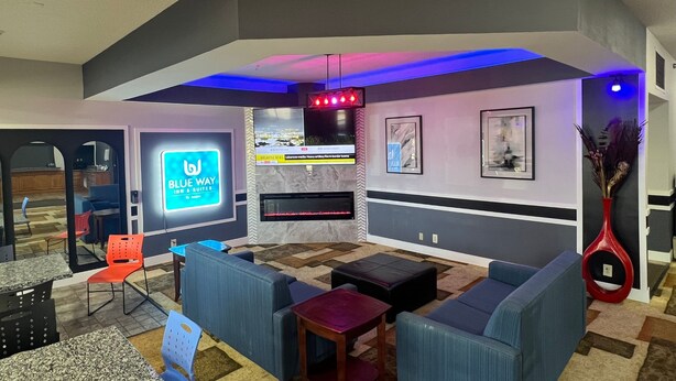 Un espace de détente moderne, doté de sièges confortables, d’une cheminée et d’un écran de télévision affichant le nom de l’hôtel.