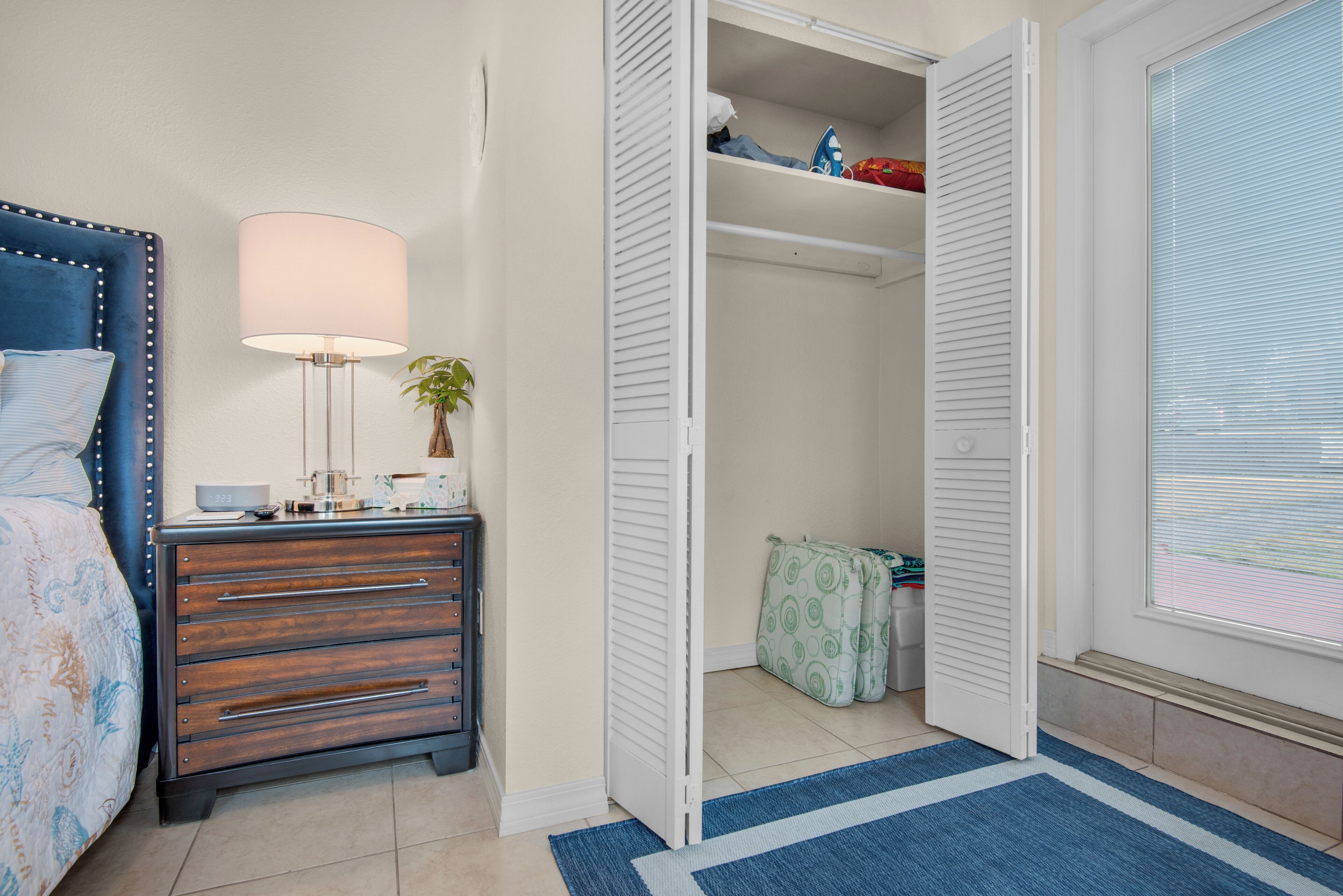 Une chambre à coucher avec un lit, une table de chevet, une lampe et une armoire dont les portes sont ouvertes.
