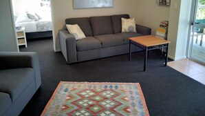 A modern living room with a grey sofa, a wooden coffee table, and a colorful rug.