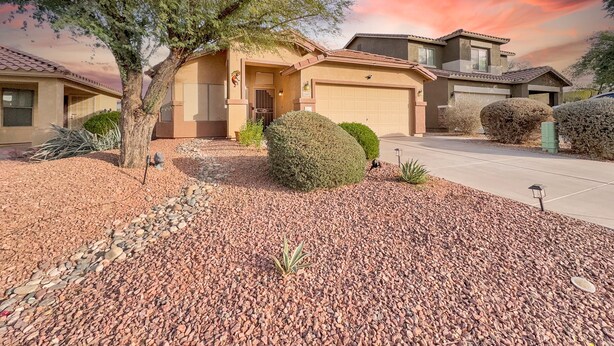 A residential house with a garage, a driveway, and a well-maintained front yard with a tree and shrubs. - 3BR w private yard, grill, garden view (San Tan Valley)