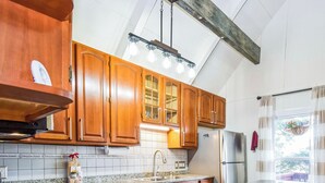 Una cocina con armarios de madera, encimeras de granito, refrigerador de acero inoxidable e isla integrada con taburetes de bar.