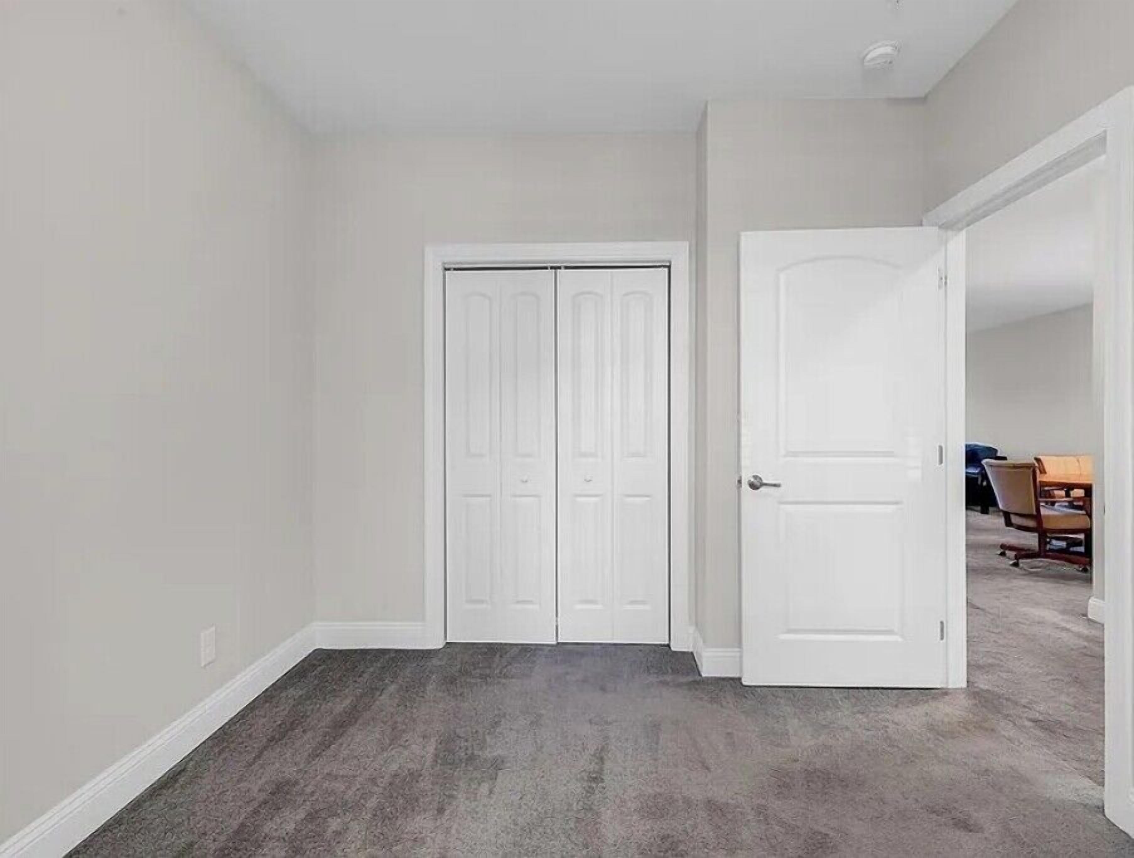 A hallway with two white doors, carpeted flooring, and a plain wall.