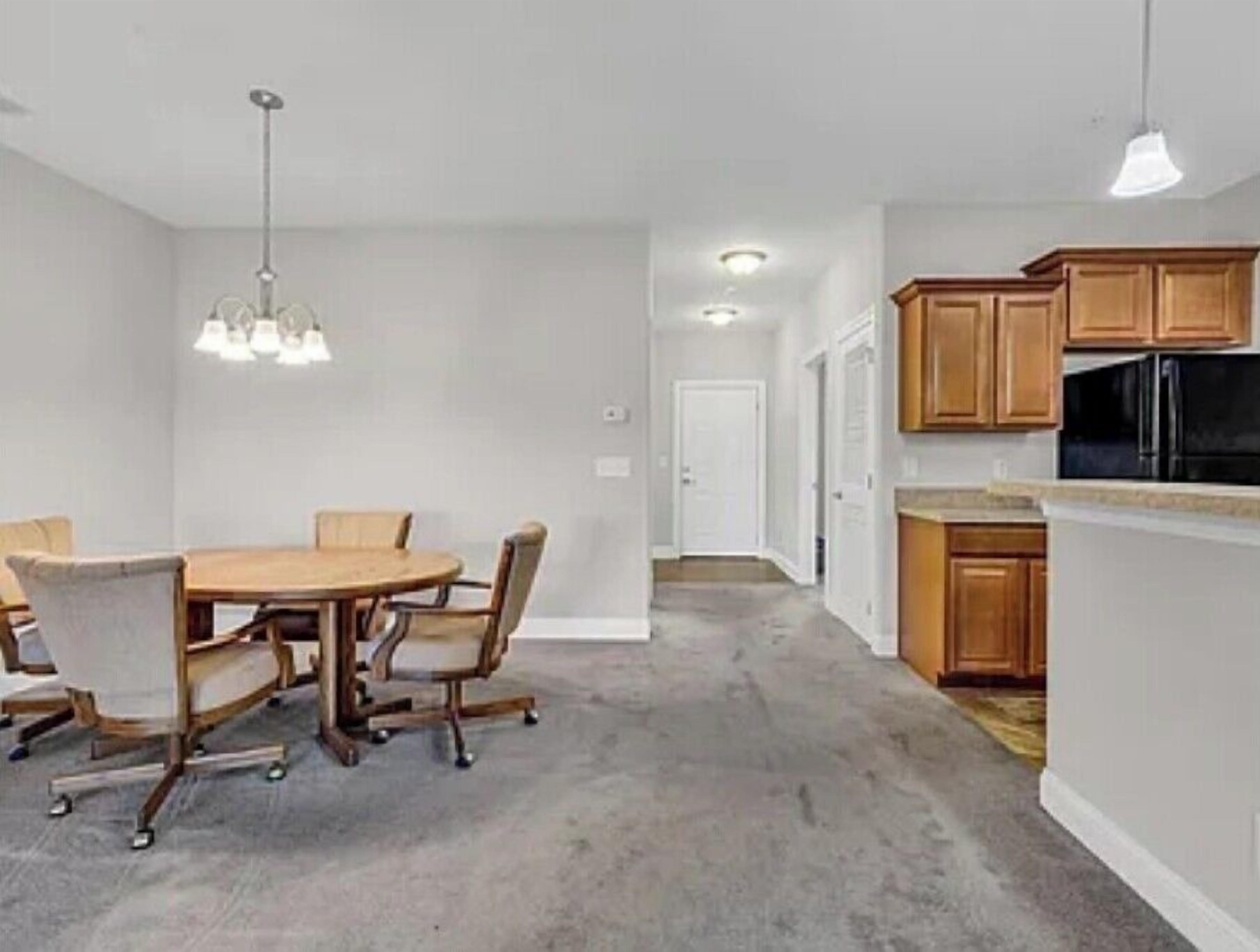 A modern kitchen with wooden cabinets, a black refrigerator, and a dining area with a round table and chairs.