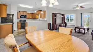 Een ruime woonkamer met een grote houten eettafel, een open haard en uitzicht op de omgeving.