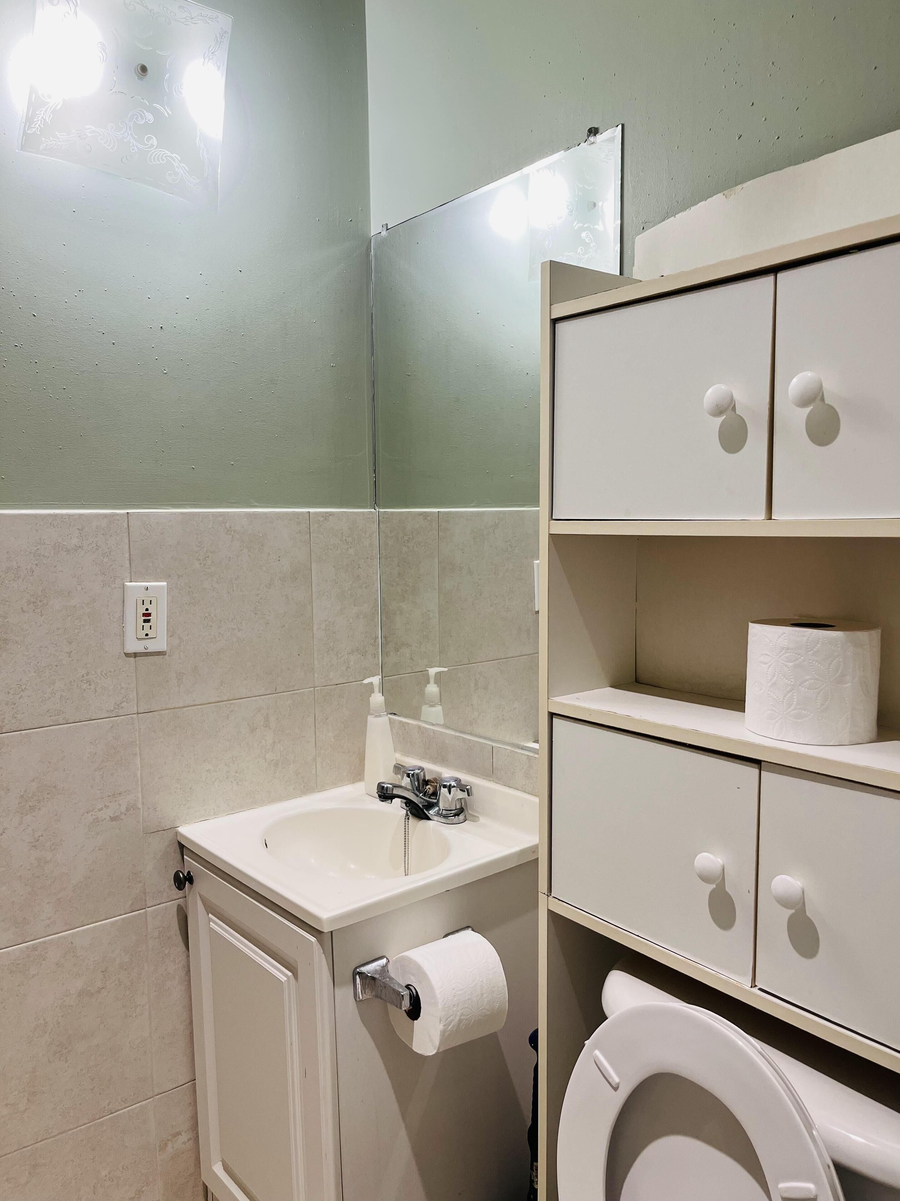 A bathroom with a sink, toilet, and storage cabinets.