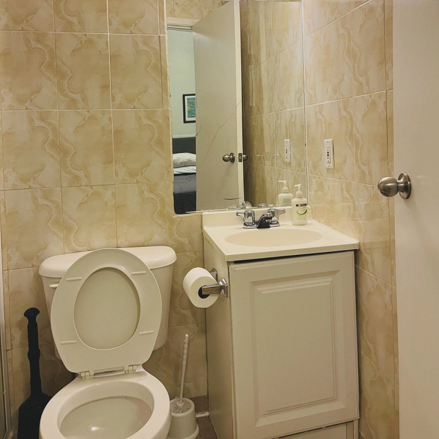 A bathroom with a toilet, sink, and mirror.