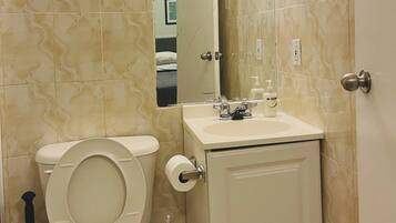 A bathroom with a toilet, sink, and mirror.