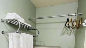 Un baño con un toallero de metal que sostiene dos toallas blancas, un secador de pelo color beige y una unidad de estantería metálica.