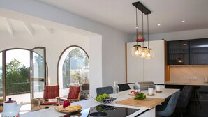 A modern kitchen with a central island, dining area, and large windows. - Gasparet by Interhome (Calpe/Calp)