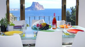 A dining table with a view of the sea and a mountain, set with plates, glasses, and a bottle of wine. - Gasparet by Interhome (Calpe/Calp)