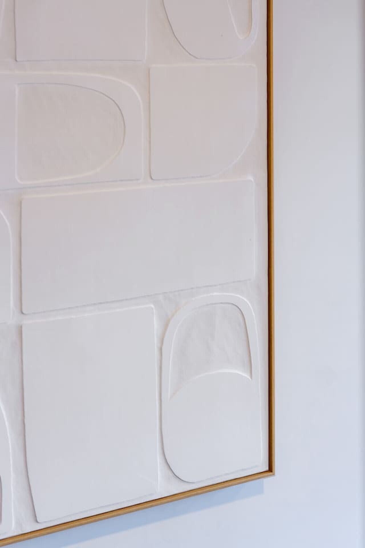 Ein gerahmtes abstraktes Kunstwerk mit geometrischen Formen an einer weißen Wand.