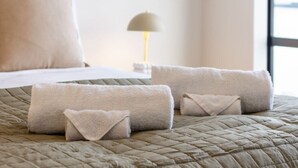 Una cama bien hecha con una colcha acolchada y tres toallas dobladas encima.