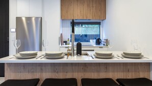 Una cocina moderna con una isla central, taburetes de bar y un refrigerador de acero inoxidable.