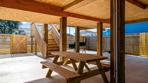 Une terrasse en bois avec des tables de pique-nique et un escalier menant à un niveau supérieur.