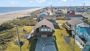 Een woongebied aan de kust met huizen, een strand en een vuurtoren op de achtergrond.