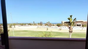A balcony with a view of a green lawn, palm trees, and buildings in the distance. - Hostal Hab 13, En Zona Hotelera, Campo de Golf, Balcón Privado, Barra y Playa (San José del Cabo)