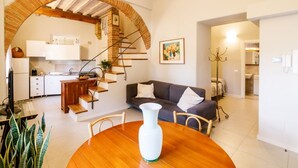 Un intérieur moderne comprenant un coin repas, une cuisine et un espace de vie, avec une entrée en briques en arc de cercle et un escalier.