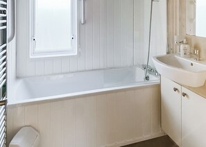 Ein Badezimmer mit einer Badewanne, einem Waschbecken und einem Fenster.