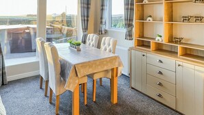 A dining area with a table, chairs, a buffet, and a view through a window.