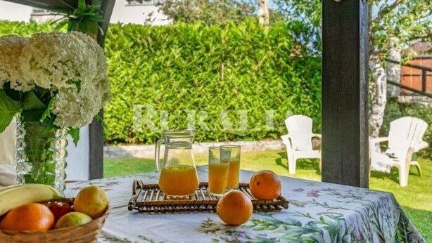 Un tavolo con frutta, un boccale e dei bicchieri, all'aperto con vista giardino.