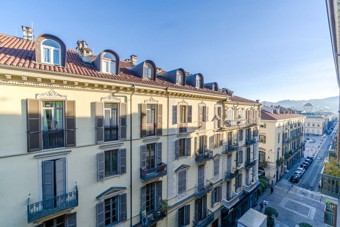 Eine Reihe mehrstöckiger Gebäude mit Balkonen, ein klarer Himmel und eine Straße im Hintergrund.