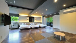 Una habitación de hotel moderna con una cama grande, zona de estar y vistas a zonas verdes.
