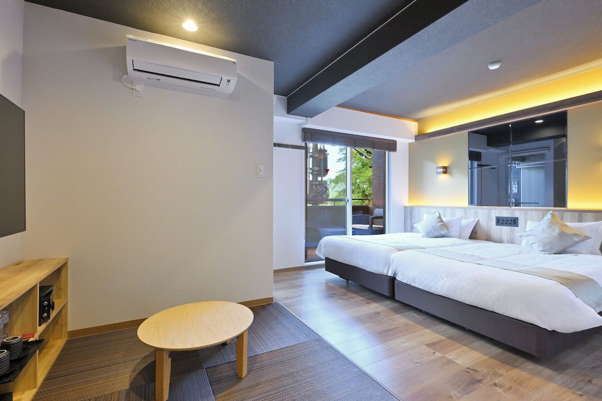 A modern hotel room with a large bed, a small round table, and a built-in air conditioning unit.