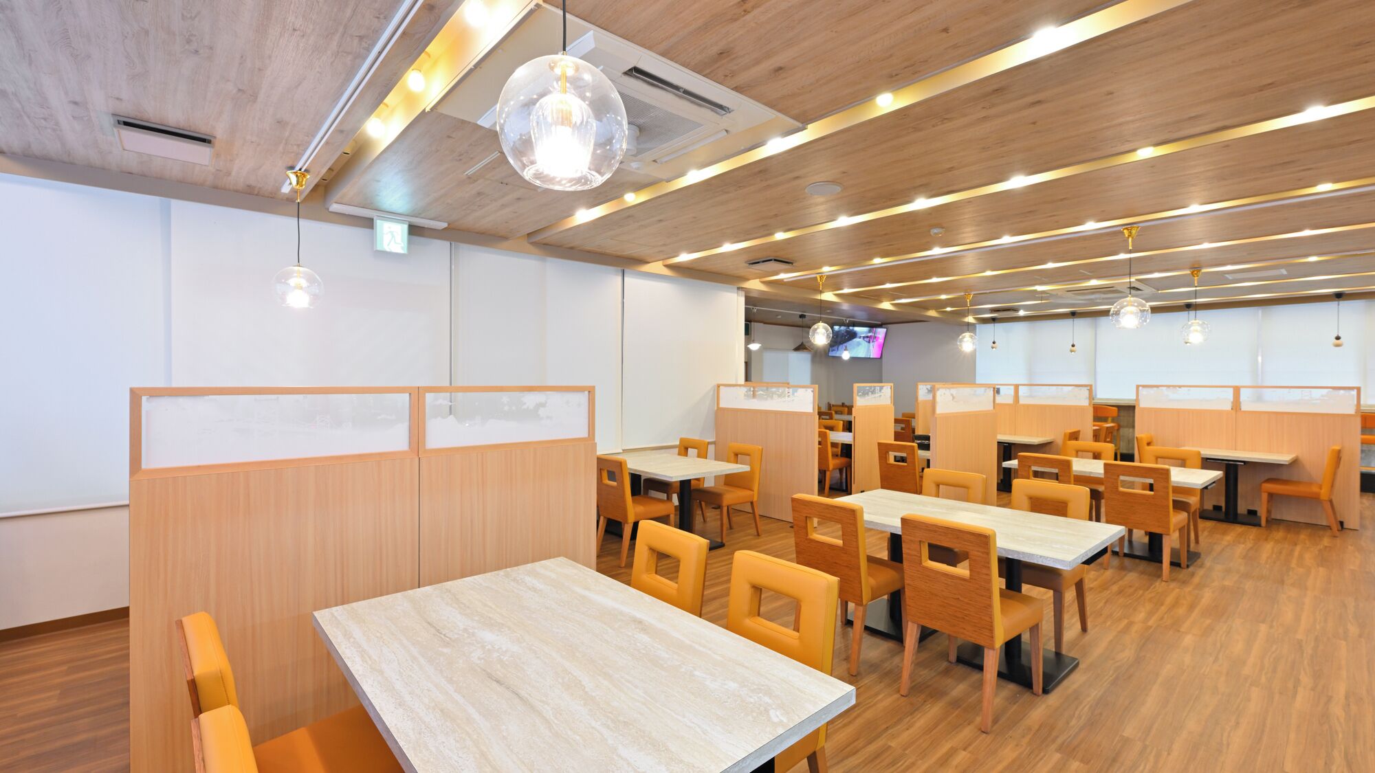 Een modern restaurant met houten lambrisering, meerdere tafels en stoelen, en hanglampen.