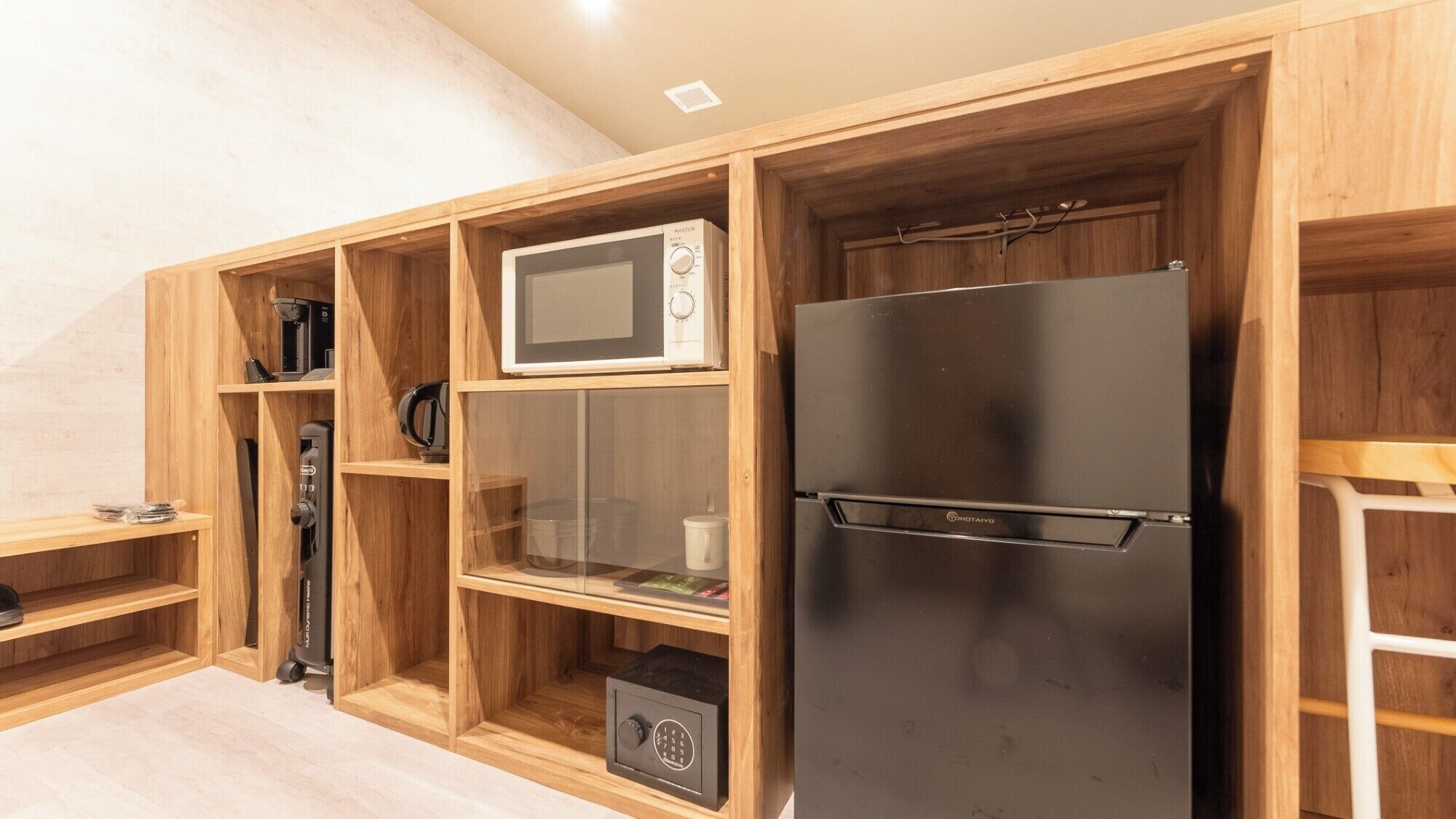 A compact kitchen with a built-in microwave, a black refrigerator, and wooden cabinetry.