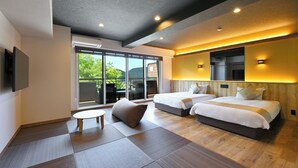 Habitación de hotel moderna con dos camas, una mesita pequeña y un amplio ventanal corredero que da a un espacio exterior.